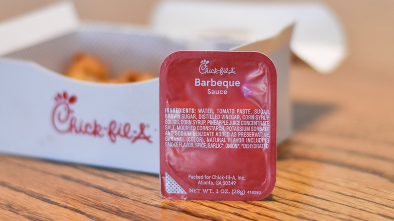 Chick-fil-A barbecue sauce in front of a box of nuggets on a wooden table