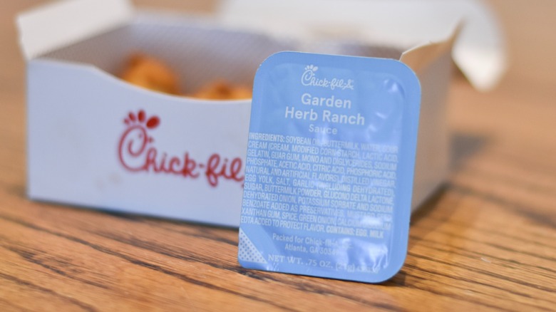 Garden herb ranch sauce in front of a box of nuggets on a wooden table