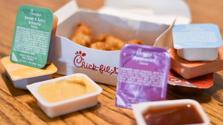 A box of Chick-fil-A chicken nuggets surrounding by dipping sauces on a wooden table