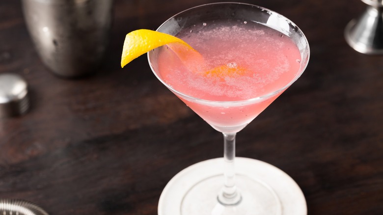 A pink cosmopolitan cocktail with a lemon twist