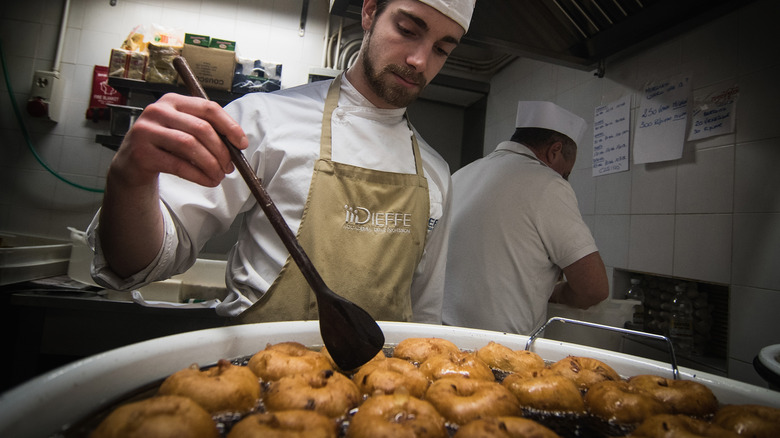 a man frying donuts in a vat