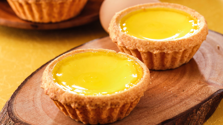 Two Hong Kong-style egg tarts on wood board