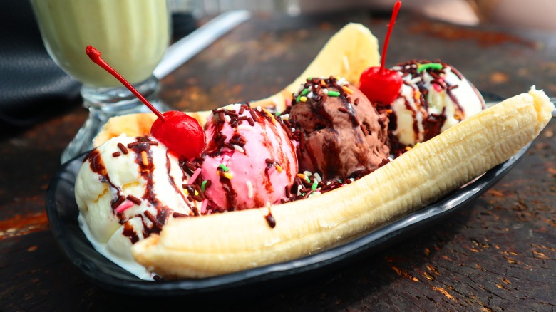 Banana split topped with ice cream, sprinkles, and cherries