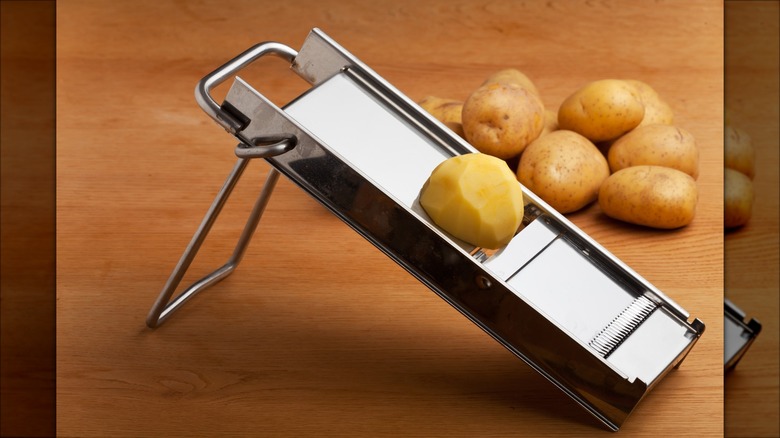 Person slicing potatoes into thin rounds with a mandolin