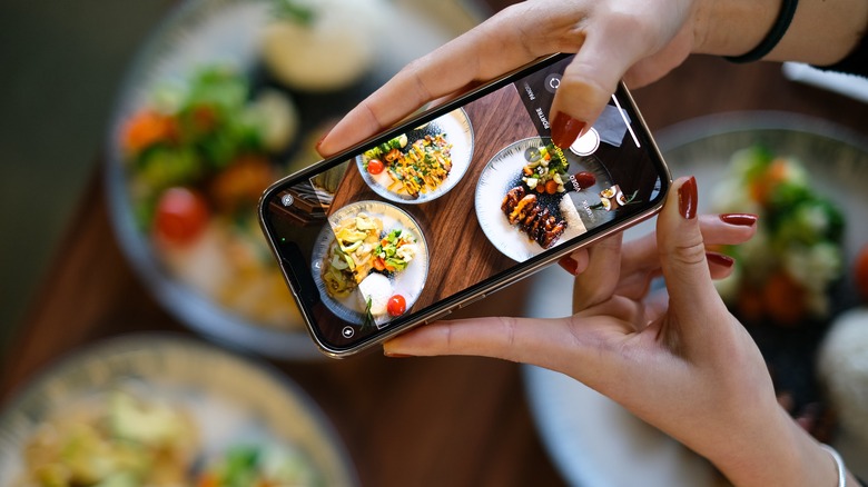 Woman photographing food with smartphone