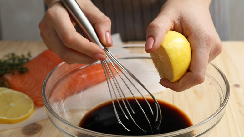 Woman squeezing lemon into bowl of soy sauce