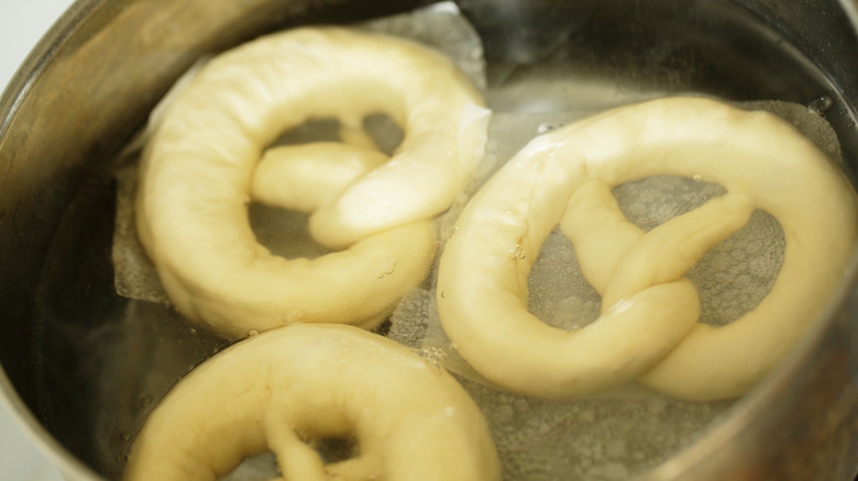 Uncooked pretzels floating in a lye bath