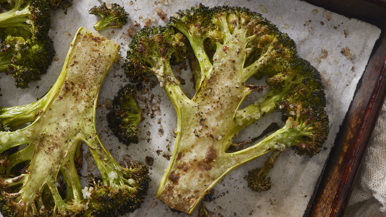 Whole roasted broccoli on an oven tray.