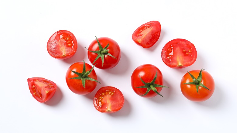 Sliced and whole cherry tomatoes on a white backdrop