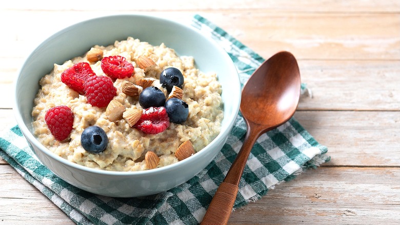 Bowl of oatmeal with raspberries, blueberries, and almonds on a checkered napkin