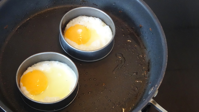 Two eggs frying in rings