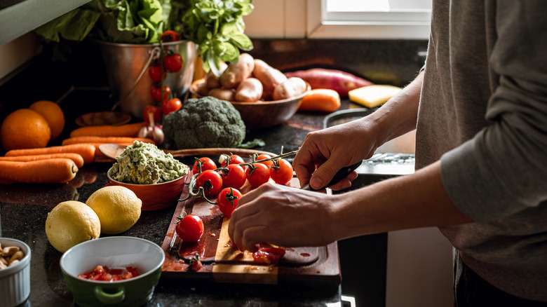 Person chopping tomatoes and other vegetables