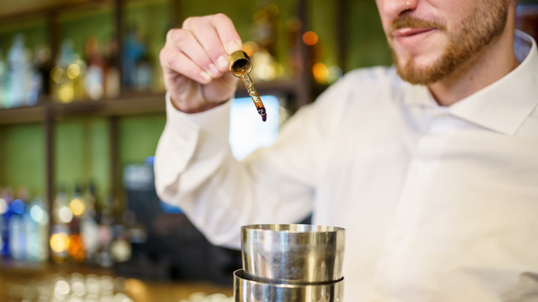 bartender adds bitters with pipette