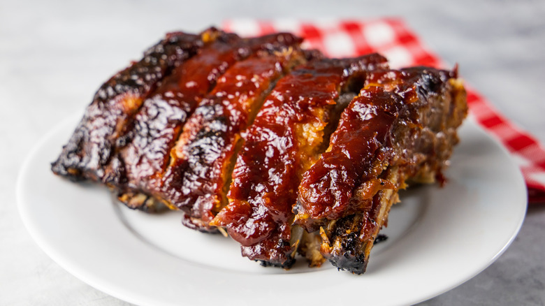 Rack of saucy barbecue ribs on a white plate