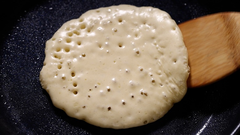 Bubbling pancake batter cooking on a hot pan