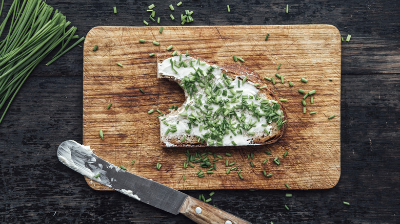 Toast with cream cheese and chives on cutting board