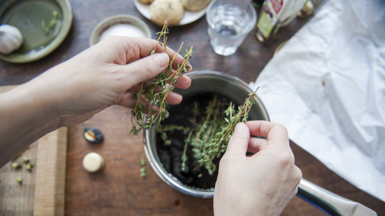 holdings holding thyme over pot