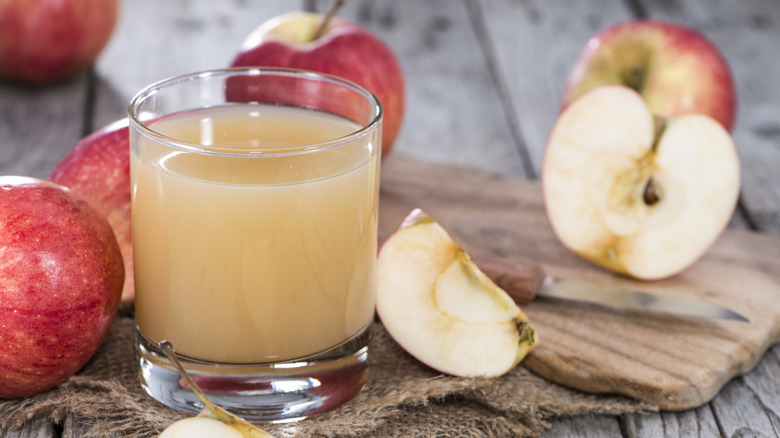 Glass of cloudy apple juice with apples