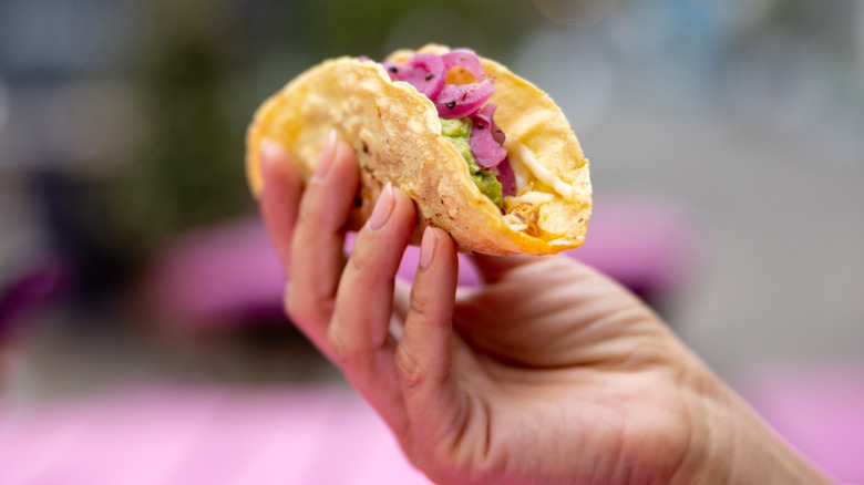Hand holding a single small taco