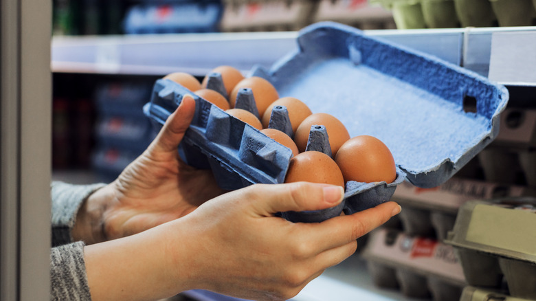 Hands holding a carton of eggs in a supermarket