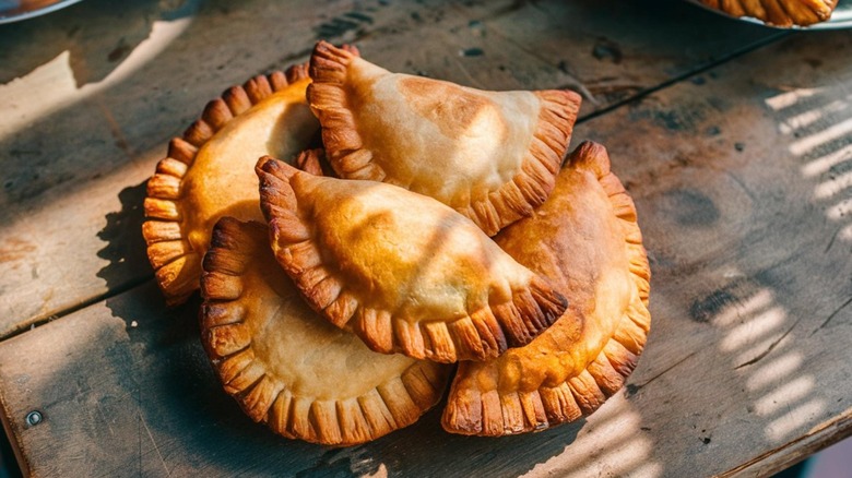 Golden brown empanadas on a wooden table