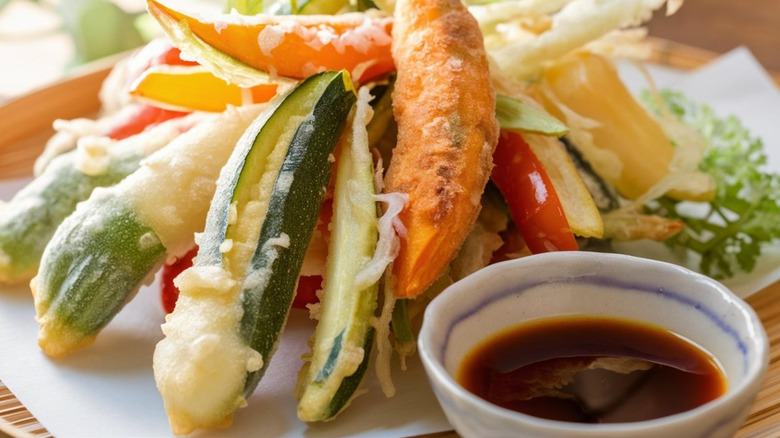 Tempura vegetables are displayed with tentsuyu sauce.