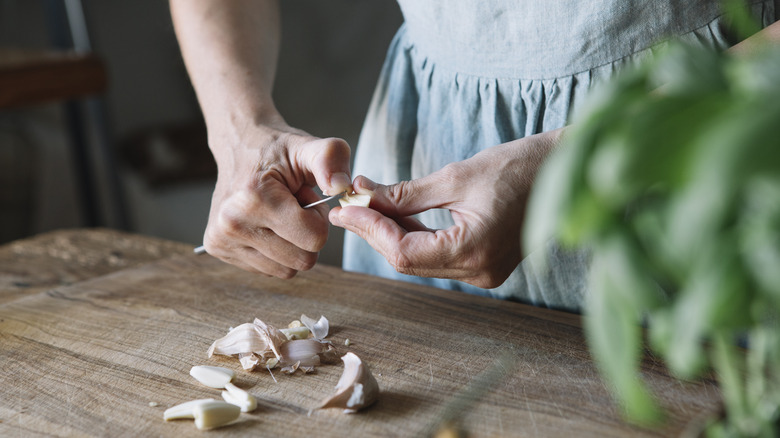 two hands peeling garlic clove