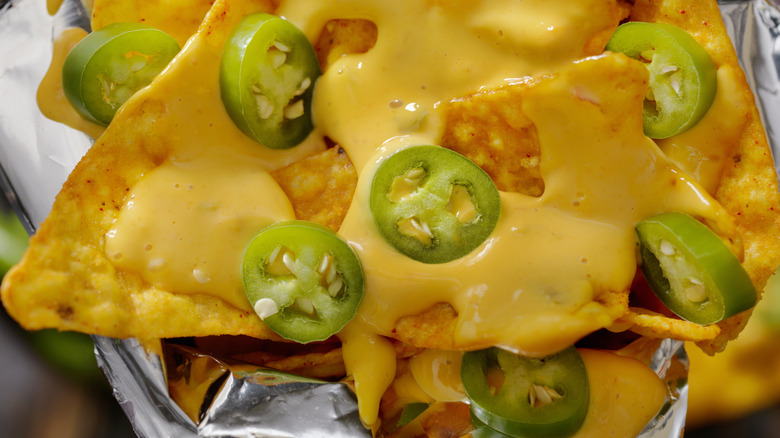 Tortilla chips covered in nacho cheese and sliced jalepeños