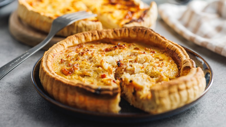 Plated quiche Lorraine with a slice cut and fork