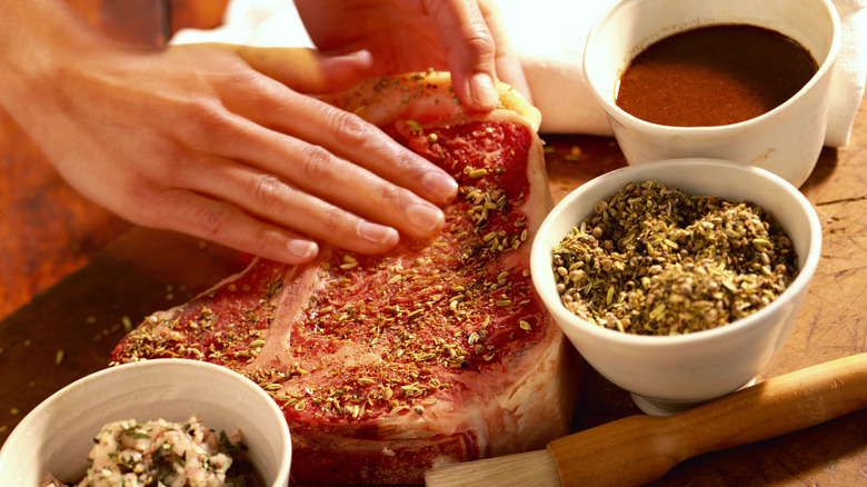 a person rubs spices onto a steak