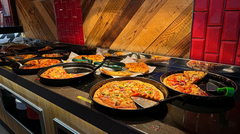 Pizza hut buffet with various pan pizzas under heat lamps