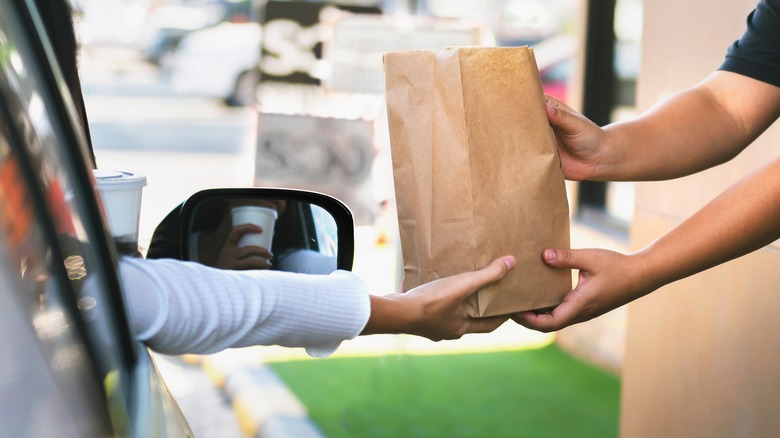 A bag of food being handed out of a drive-thru window.