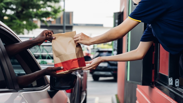 People exchanging paper bag at drive-thru