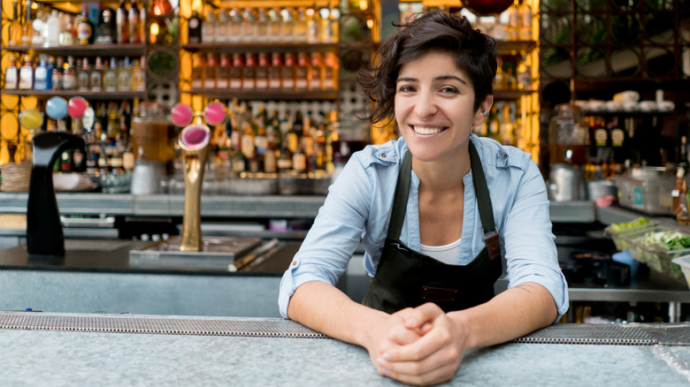 Female bartender leaning on counter