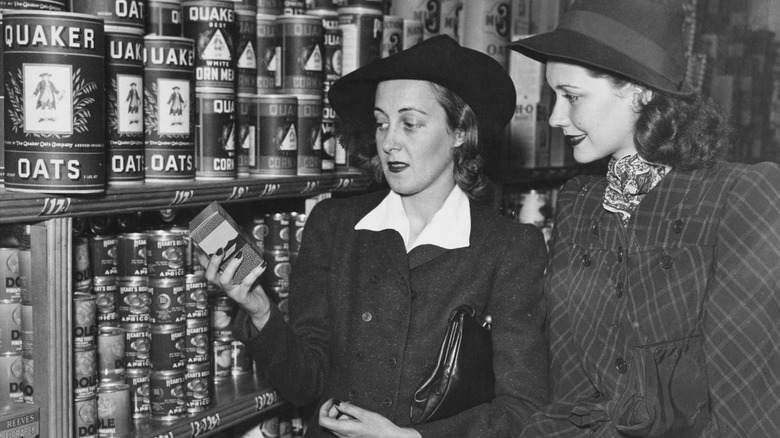 Two women shopping on shelves with the vintage Quaker Oats tins