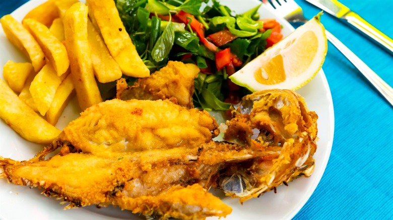 A plate with fried fish, salad, and fries