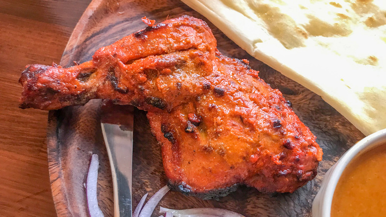 Tandoori chicken next to naan and curry