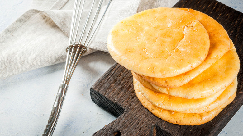 Cloud bread sits on a cutting board next to a metal whisk