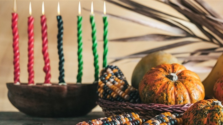 Fall and winter fruits next to Kwanzaa candleholder