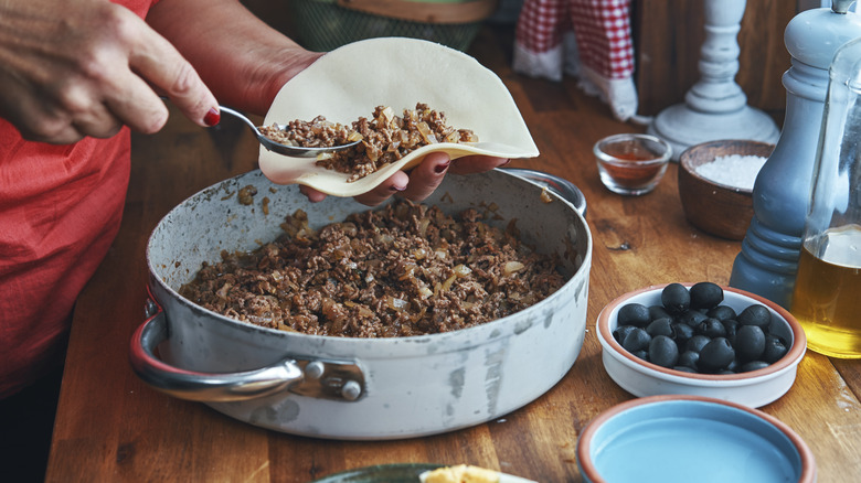 Person adding beef to tortillas