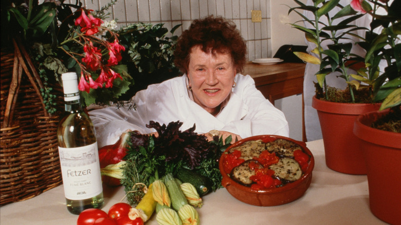 Julia Child posing with vegetables and a bottle of wine