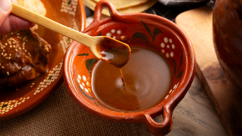 Mole poblano is stirred in a bowl.