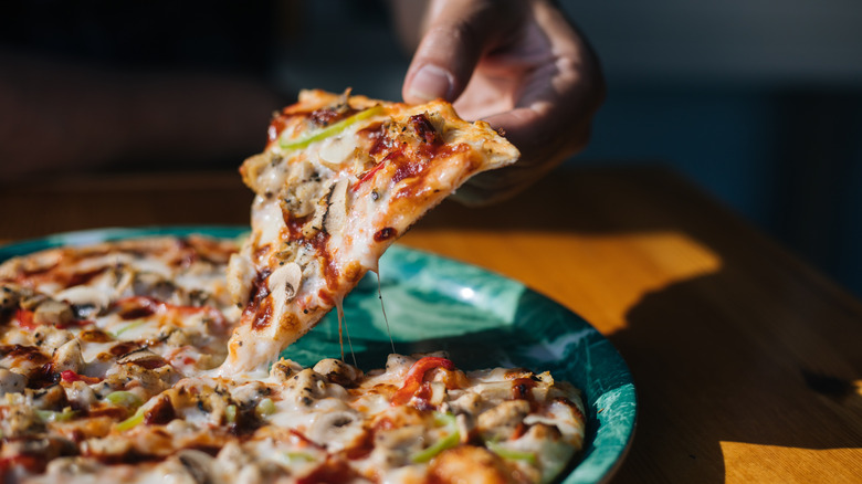 Hand lifting slice of pizza