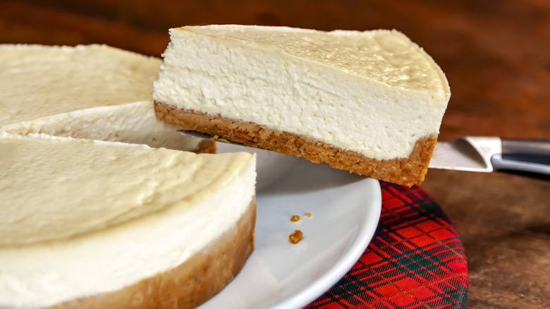 Removing a slice from a plain white cheesecake