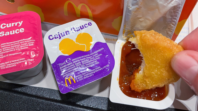 Closeup of hand dipping a nugget in sauce