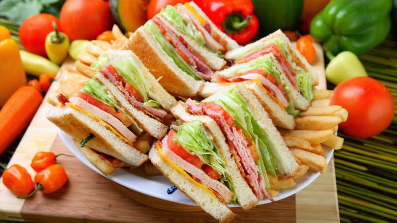 Club sandwiches on a plate of french fries surrounded by vegetables