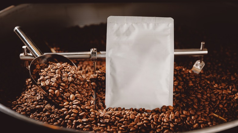 A white bag surrounded by roasted coffee beans 