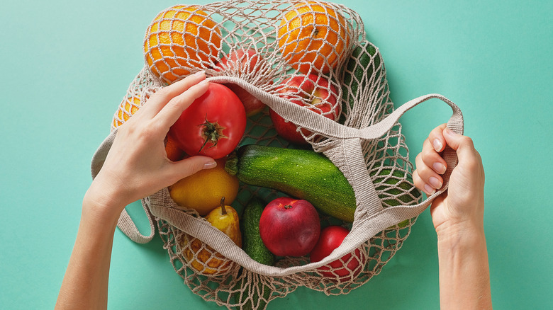 A string produce bag full of vegetables with a blue background