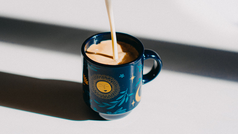 Creamer being poured into a blue decorated mug