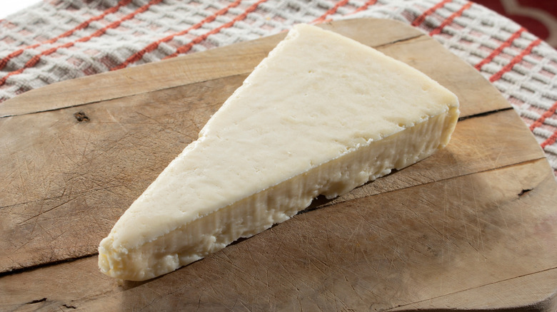 A triangle of cotija cheese sits on a cutting board.